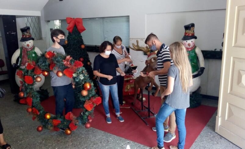 Pessoas ornamentam a porta da Prefeitura de Nova Friburgo com decorações de Natal.