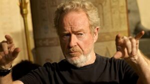 Diretor Ridley Scott usando camisa preta em fundo bege